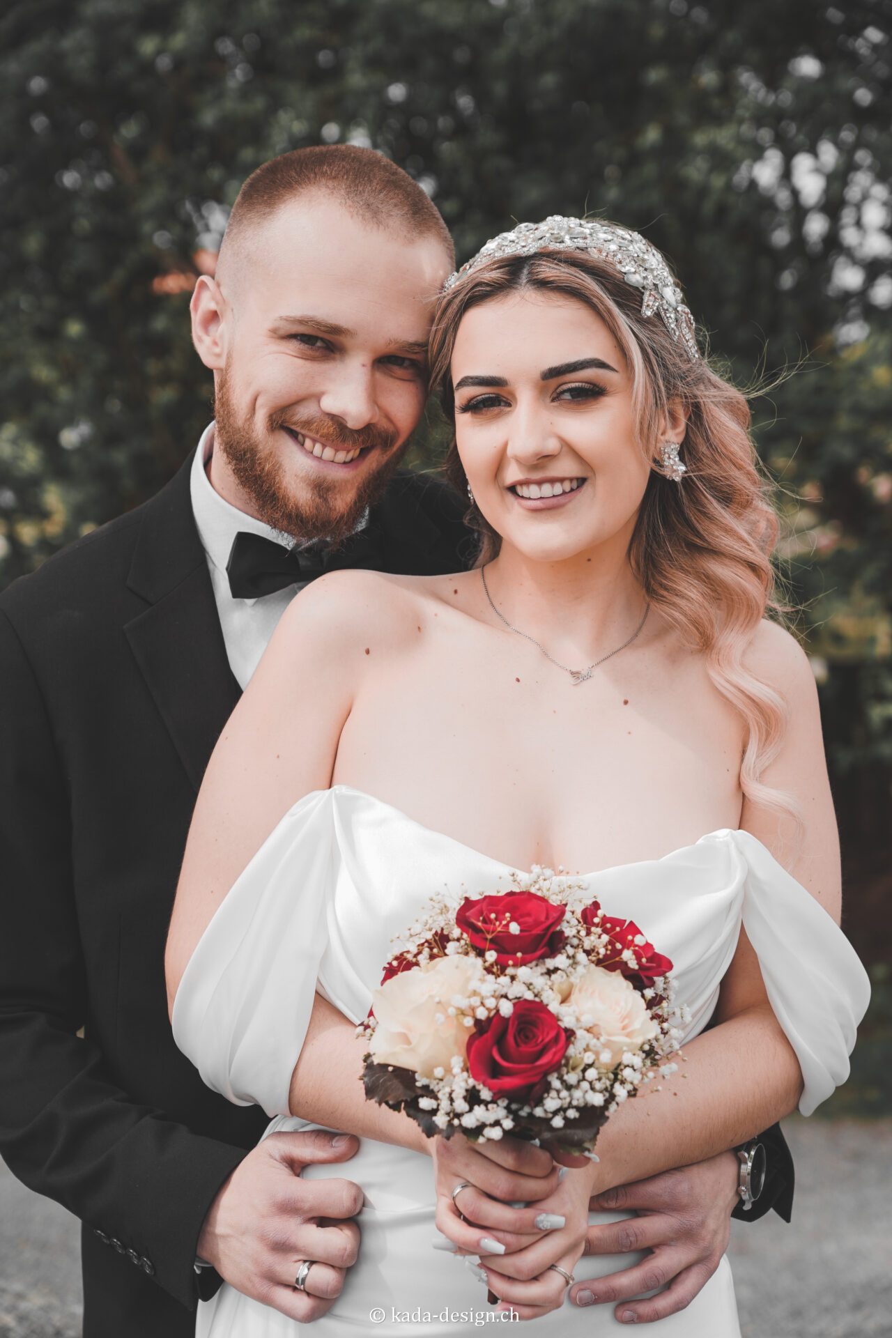 Brautpaar mit Blumenstrauß lächelt.