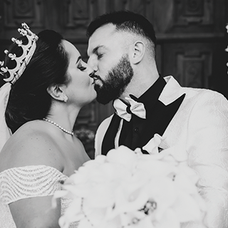 Brautpaar küsst sich, Hochzeitstag, schwarz-weiß Fotografie.